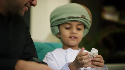 Omani father and son inserting money in money jar. Stock Footage 151271559