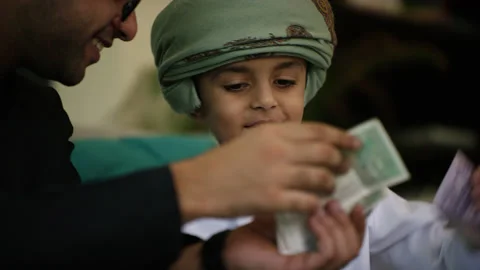 Omani father and son inserting money in money jar. Stock Footage 151277238