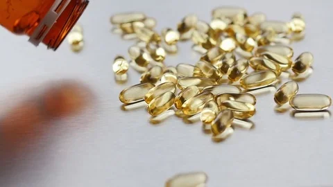 Omega 3 capsules falling on a metal surface Stock Footage 72372103