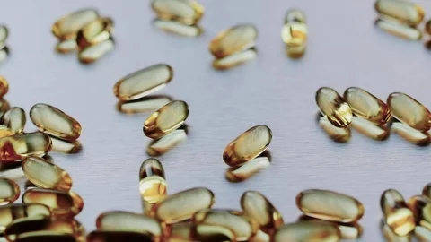 Omega 3 capsules falling on a metal surface Stock-Footage 72372223