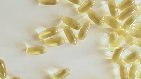 Omega 3 capsules falling on table Stock Footage 101738707