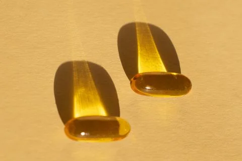 Omega 3 capsules lying and shadows on beige background. Fish oil in pills. Stock Photos