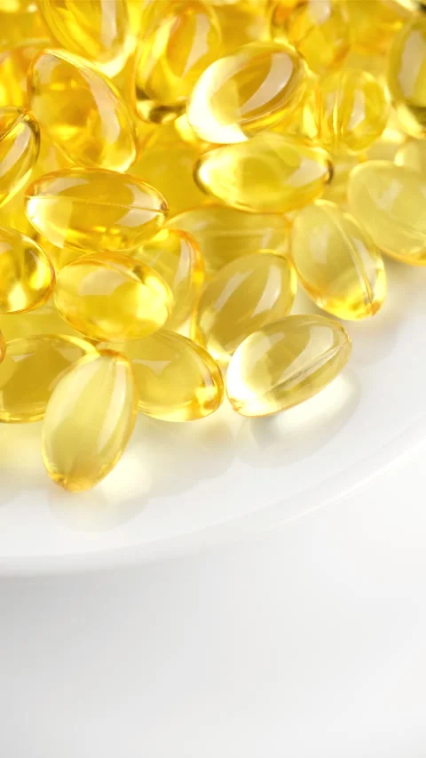 Omega 3 capsules or fish oil, in white plate, rotation Stockbeeldmateriaal 277481384
