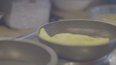 An omelet is being moved and prepared on a fancy pan in the kitchen. Stock Footage 141078257