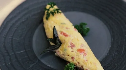 Omelette with ready-made vegetables on black plate in slow motion Stock Footage 77480769