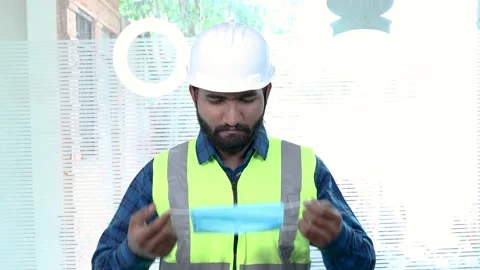 Omicron virus, Worker engineer putting on  protective mask on face stand Stock Footage 136207469