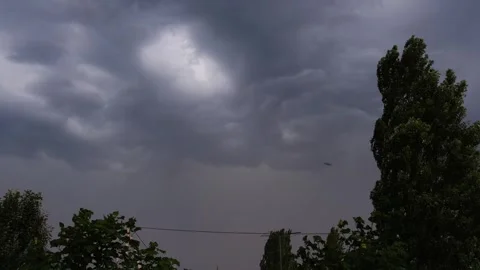 Ominous dark thunderstorm clouds flashing with hidden lightning in dramatic s Vídeos de archivo 338198265