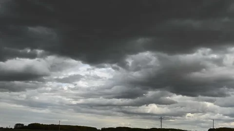 Ominous gray storm clouds move above a rural setting with trees and power poles  Stock Footage 151834735