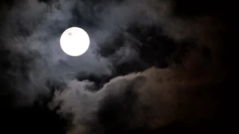 Ominous scene with full moon in dark night sky and dark passing clouds Video stock 320084651