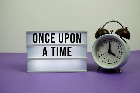 Once Upon a Time text on light box with alarm clock on purple background Stock Photos