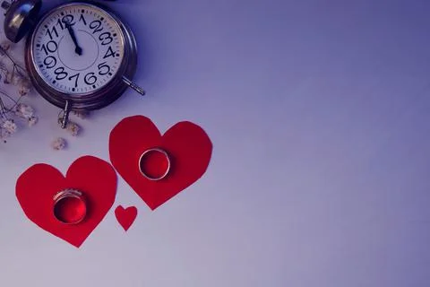 One alarm clock with two wedding rings and two red hearts for Valentine's Day Stock Photos