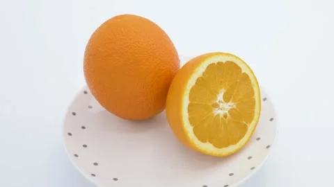 One and a half orange on a rotating plate with grey dots - white background Stock Footage 145813769