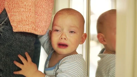 One and a half year old baby cries standing near his mother. The child asks for Stock Footage 121278885