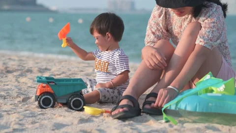 One and half year old baby boy playing with toys on the beach accompanied b.. Stock Footage 336494236