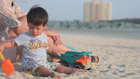 One and half year old baby boy playing with toy truck on beach Stock Footage 336494328
