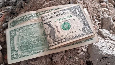 One and two dollar bills resting on rough concrete ground Stock Photos