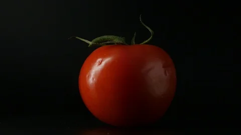 One appetizing ripe tomatoes on a mirror black background. Rotating table 動画素材 108826972