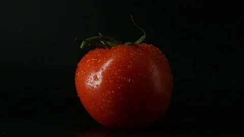 One appetizing ripe tomatoes on a mirror black background. Rotating table 動画素材 108826978