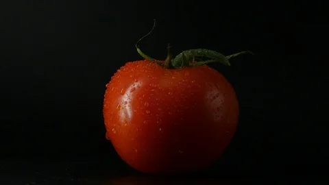 One appetizing ripe tomatoes on a mirror black background. Rotating table 動画素材 108827004