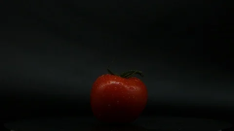 One appetizing ripe tomatoes on a mirror black background. Rotating table 動画素材 108827409