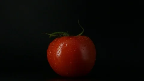 One appetizing ripe tomatoes on a mirror black background. Rotating table 動画素材 108827600