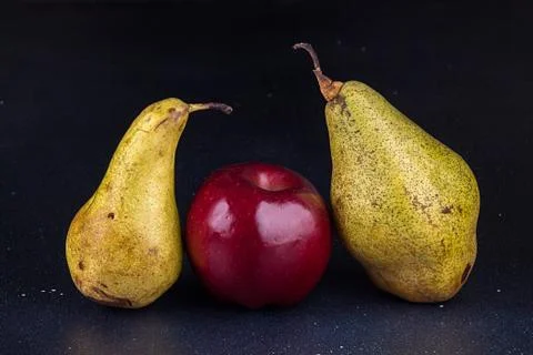 One apple and two pears on darc background. Homegrown organic fruits. Stock Photos