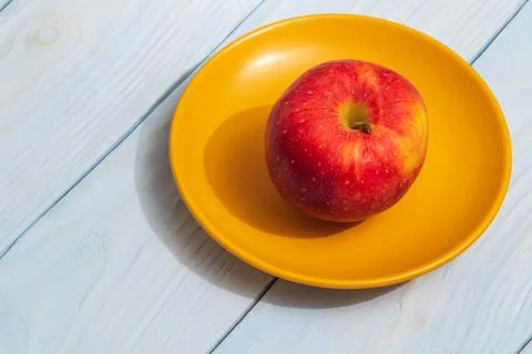 One apple on orange plate. The idea of fasting diet after the holidays Stock Photos