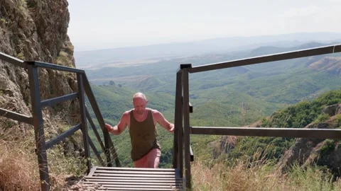 One bald guy is hiking in the mountains on a sunny bright day Stock Footage 248870257