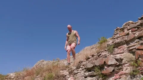 One bald guy is hiking in the mountains on a sunny bright day Stock Footage 248871245
