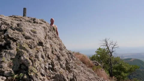 One bald guy is hiking in the mountains on a sunny bright day Stock Footage 248887984