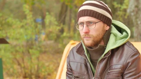 One bearded man lights a cigarette on a bench in autumn park. Thoughtful serious 動画素材 68971240
