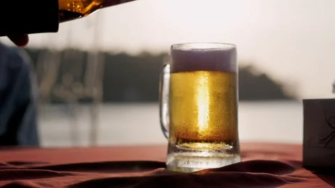One beer cup with the setting sun in the background. Beer pouring from a bottle Stock-Footage 127152008