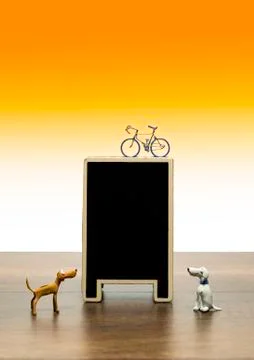 One bicycle model on top blank black board with two clay dogs Stock Photos