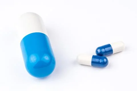 One big capsule looking like a big blue and white pill two little pills Stock Photos