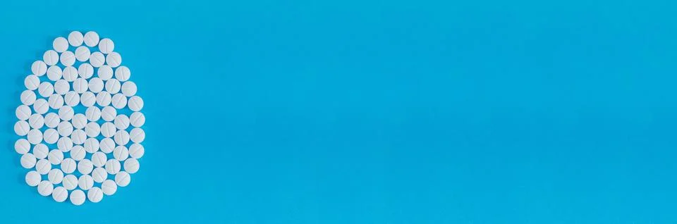 One big Easter egg made from medical pills on blue background. Stock Photos