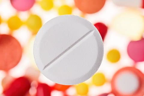 One big tablet (pill) macro view on blurred multicolored drugs background, me Foto stock
