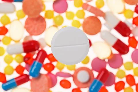 One big tablet (pill) macro view on blurred multicolored drugs background, me Stock Photos