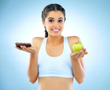 One bite wont hurt...Studio shot of a woman deciding between healthy and Stock Photos