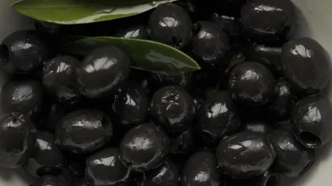 One black pitted olive falling into pile in macro close up Vídeos de archivo 335003347