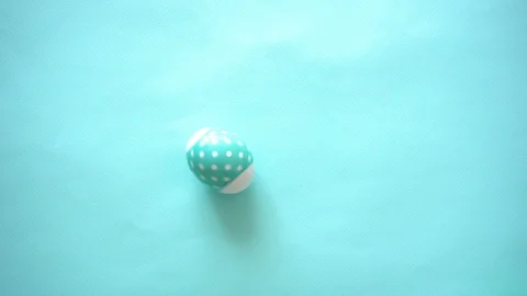 One blue easter egg with pea, spinning chaotically as if boiled against a blue Stock Footage 112392914