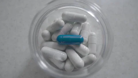 One blue pill on isolated background. Medicine tablets. Capsule inside bottle. Stock Footage 254462856