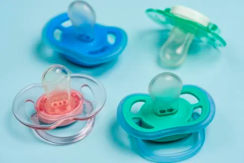 One blue plastic nipple pacifier soother on a blue background, space for text Stock Photos