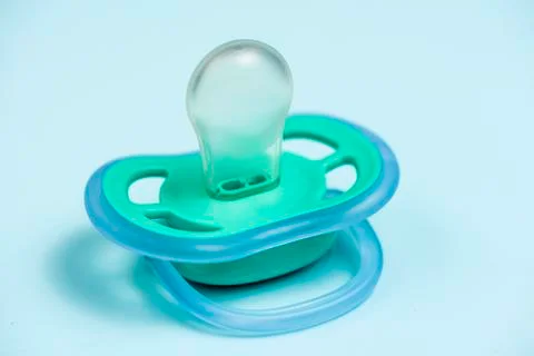 One blue plastic nipple pacifier soother on a blue background, space for text Stock Photos