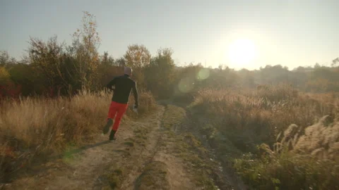 One bold young man running on dirt road holding a map in hand wearing black long Stock Footage 166158540