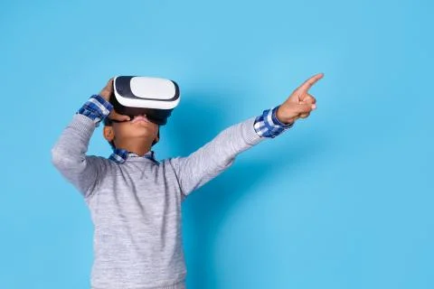 One boy studio isolated on blue wall looking into virtual reality headset Stock Photos