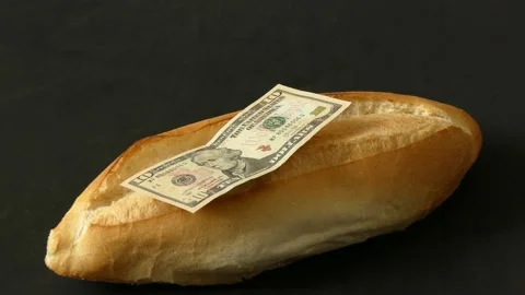 One bread and 10 US dollar bills on it, bread price hike, increased bread p.. Stock Footage 237255387