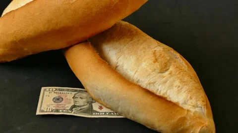 One bread and 10 US dollar bills on it, bread price hike, increased bread p.. Stock Footage 237255585