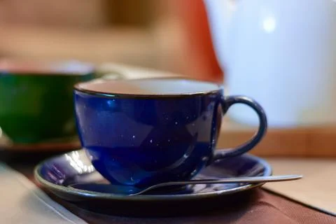 One bright deep blue colored coffee cup on platter with hot tea on table, clo Stock Photos