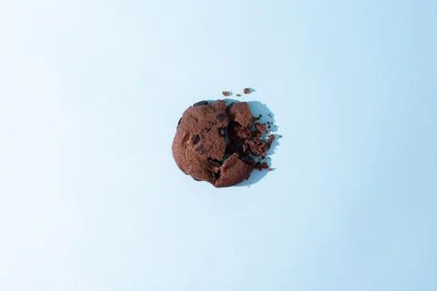 One broken chocolate chip cookie on blue background in sunlight. Foto stock