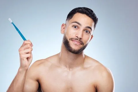 One brush away from perfection. a young man holding a toothbrush against a Stock Photos